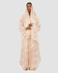 Woman wearing a sheer beige hijab with floral patterns on a white background
